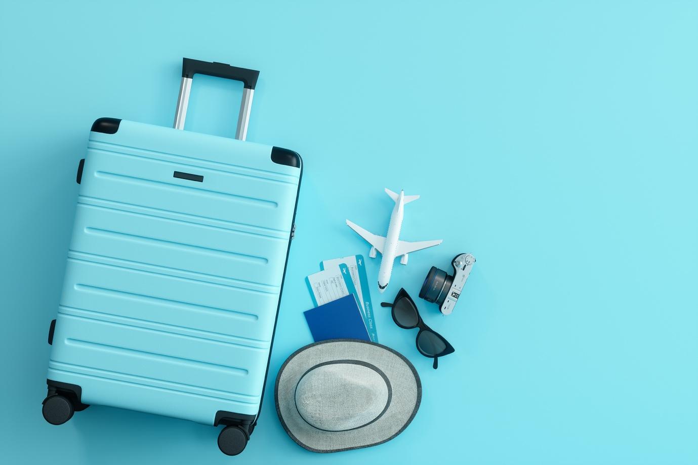 Suitcase, camera, sunglass, tickets, hat on blue background